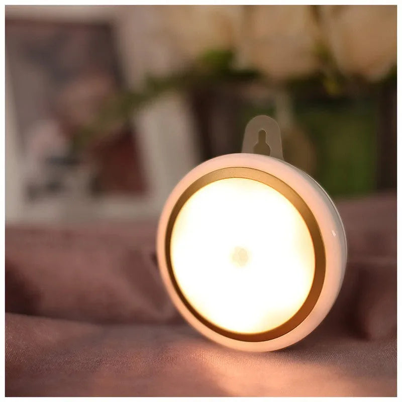Circular white motion sensor LED light with a compact design, shown mounted on a wall.