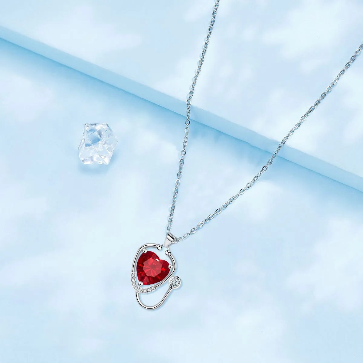 Red diamond women's necklace with stethoscope, wing, and cross pendant design on a copper chain.