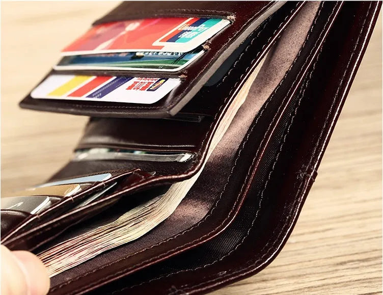 Men's black full-grain leather bifold wallet open, showing card slots, note pocket, and zipped coin compartment.