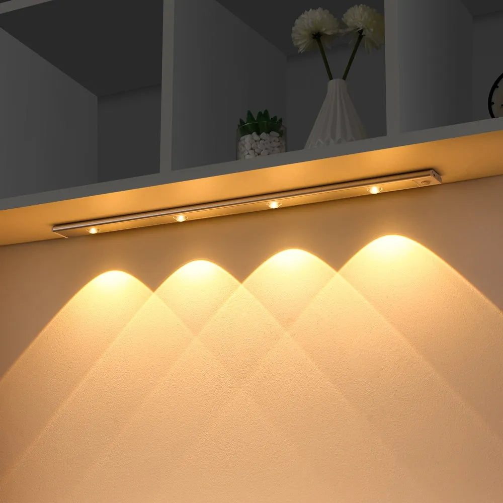 Silver ultra-thin wireless LED strip light with motion sensor attached to a kitchen cabinet door.
