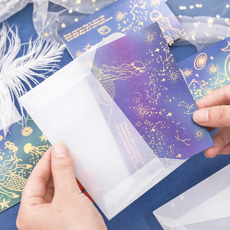 Set of three bronzing mermaid-style folded greeting card envelopes in celestial colourways, 13x8.5cm, on a light background
