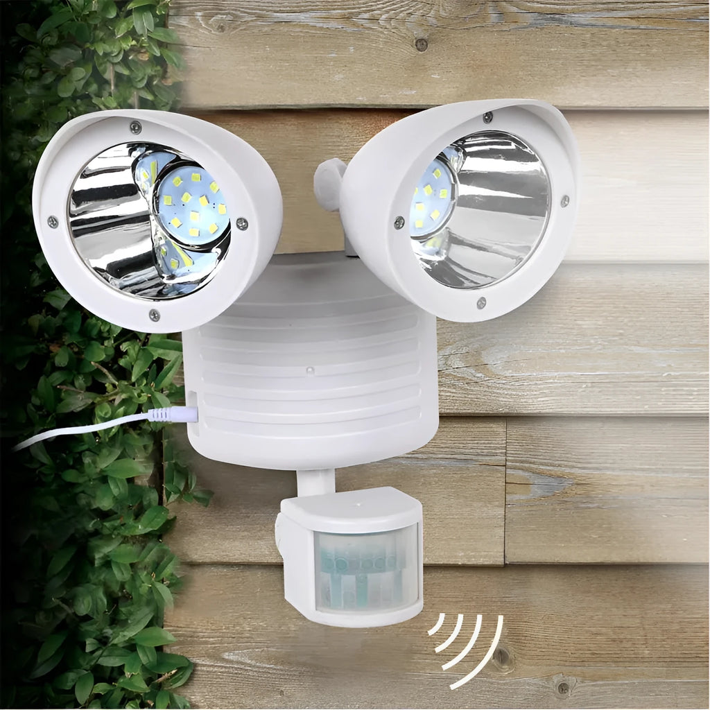 Black dual-head solar security spotlight with solar panel on top mounted on an outdoor wall.