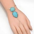 Silver alloy plated drop shape bracelet with turquoise tassel on a neutral background