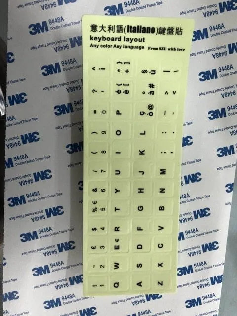 Glowing yellow multilingual keyboard stickers showing Arabic, Thai, Hebrew, French, Italian and German characters