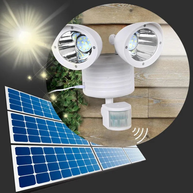 Black dual-head solar security spotlight with solar panel on top mounted on an outdoor wall.