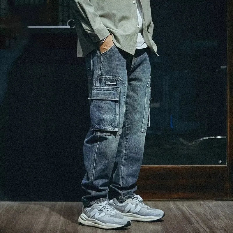 Blue men's loose straight-leg stretch denim trousers on a hanger, showing zip fly placket detail.