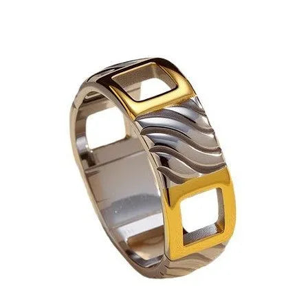Gold and silver two-tone geometric cross stainless steel ring on a light background showing texture and electroplated finish