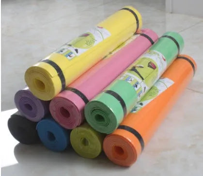 Red EVA yoga mat showing thickness, next to a blue mat, on a wooden floor.