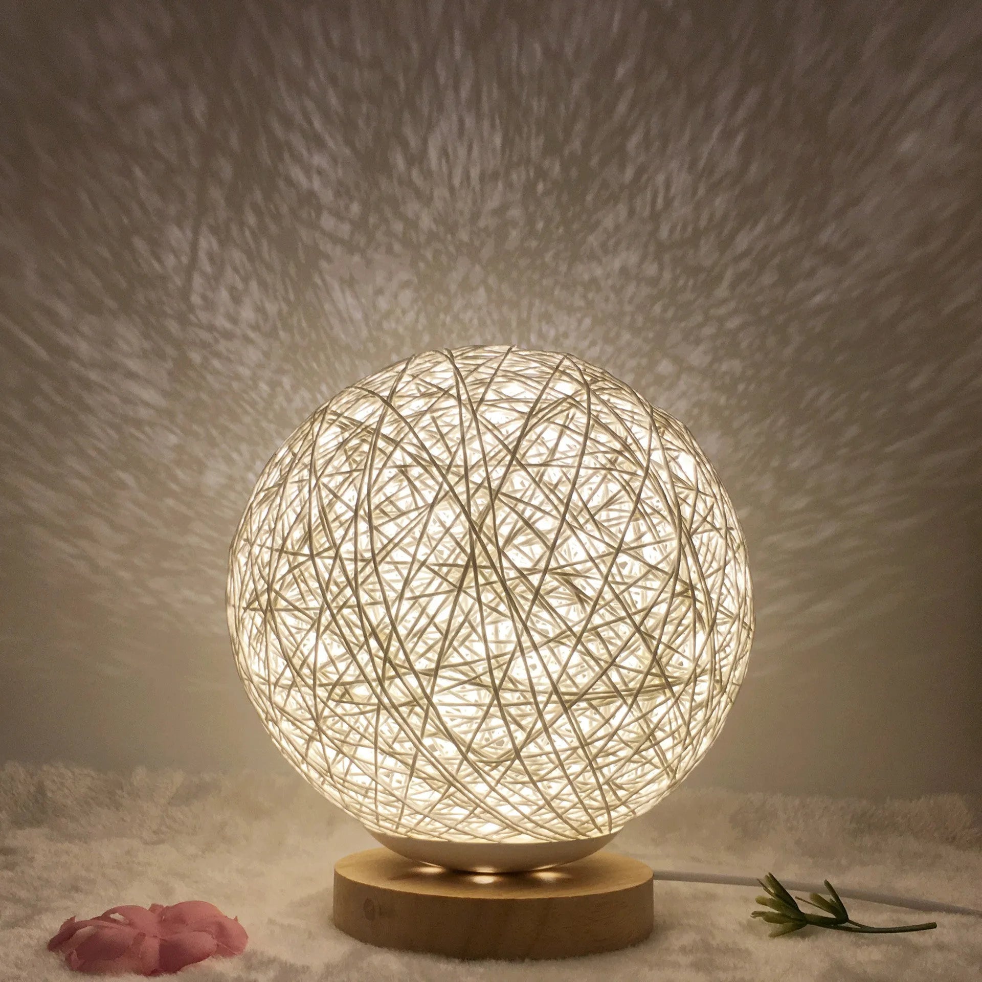 Rattan ball table lamp with woven shade and warm LED lighting on wooden surface