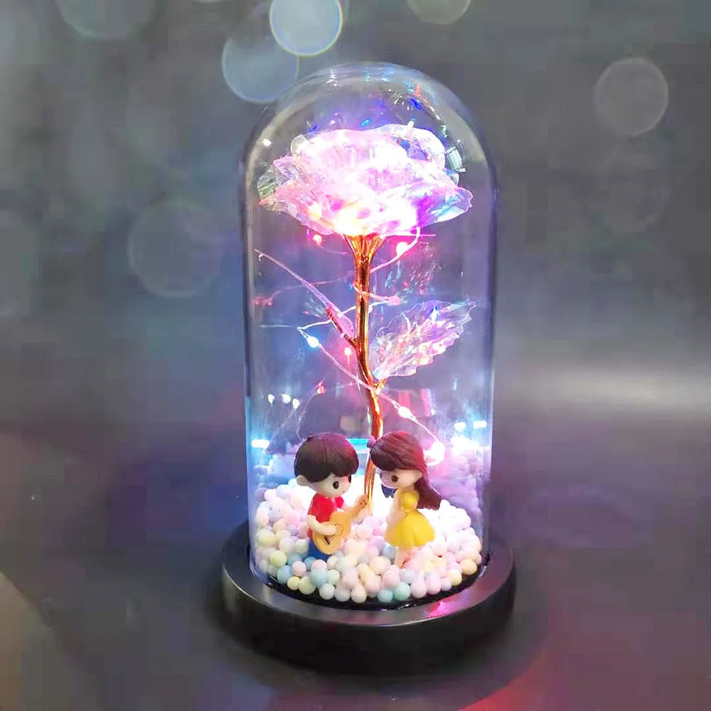 Artificial gold rose in clear glass dome on black base with LED lights for home decor