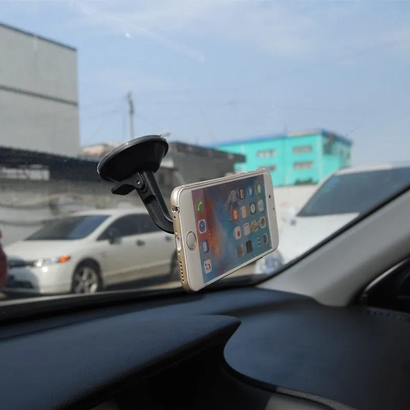 Black magnetic car phone holder mounted on dashboard with smartphone attached showing 360-degree rotation feature