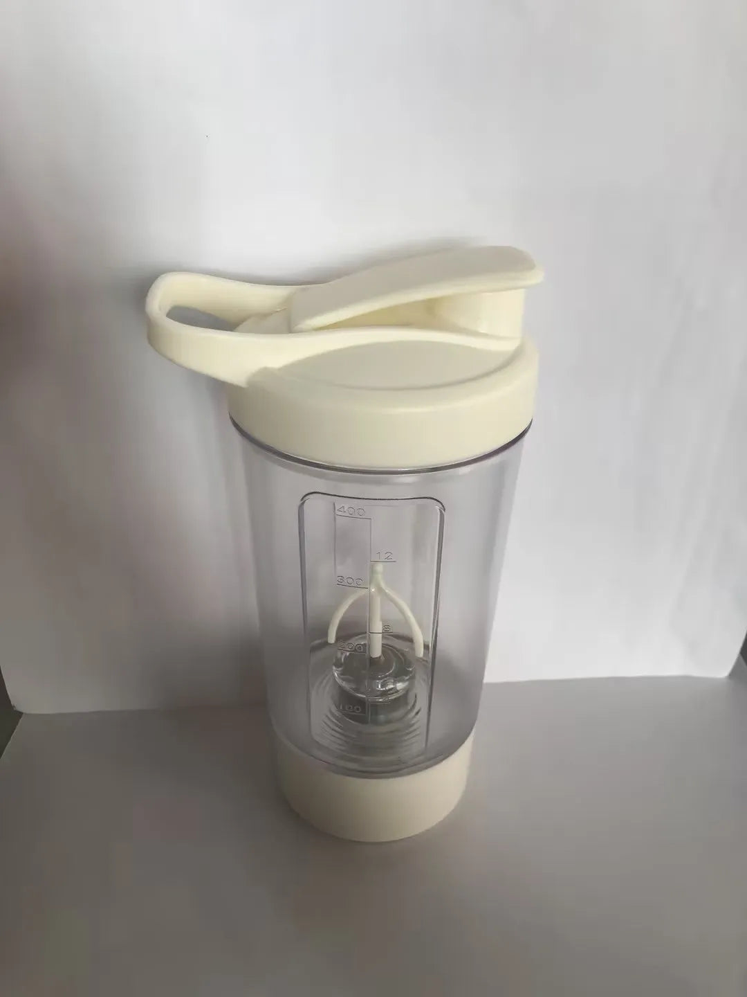 400ml electric protein shaker bottle in black with white lid and USB charging cable on a grey surface