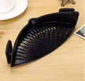 Silicone clip-on colander strainer in black with stainless steel clip attached to a pot rim for draining liquid