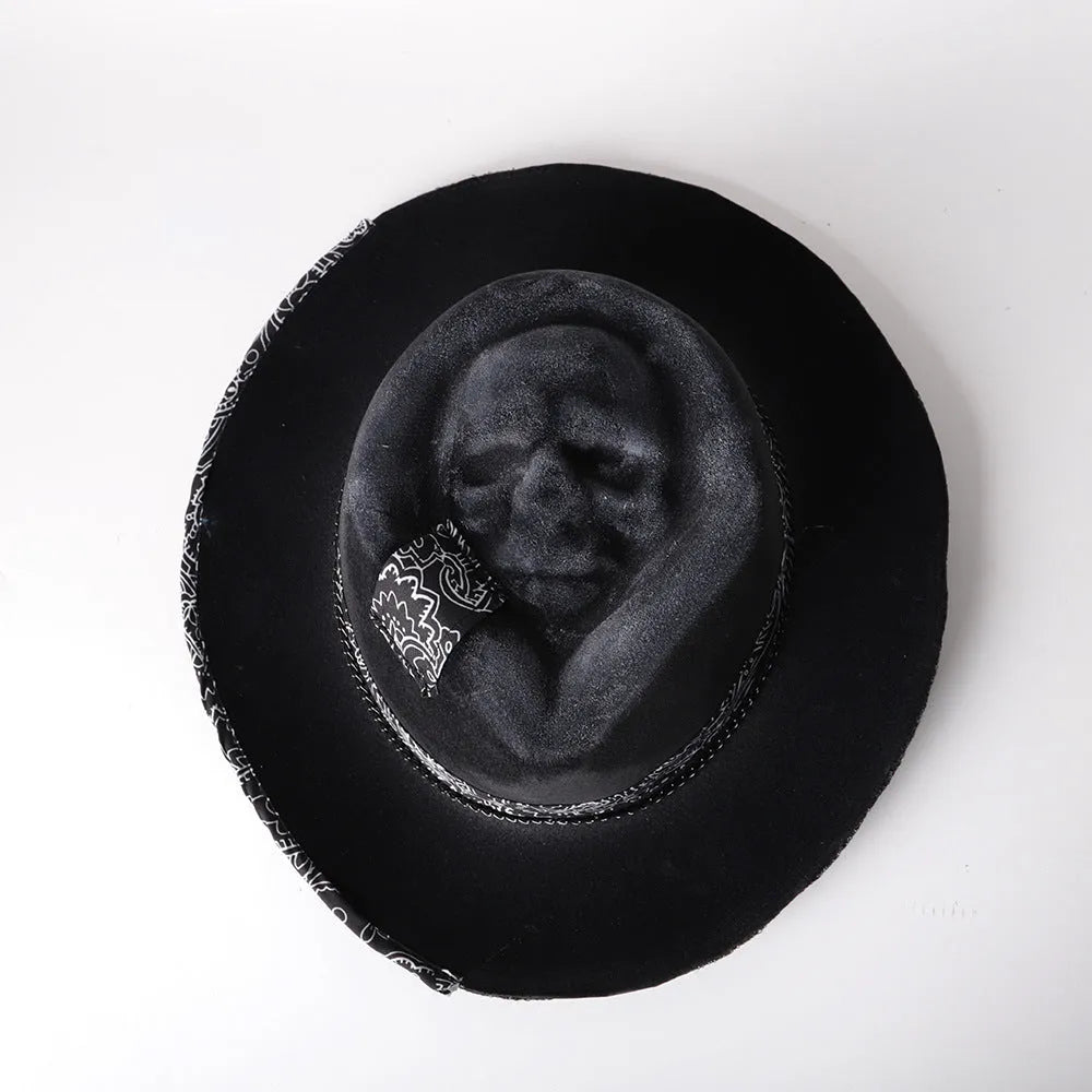 Handmade black wool felt skull hat with a pointed conical crown on a plain background.