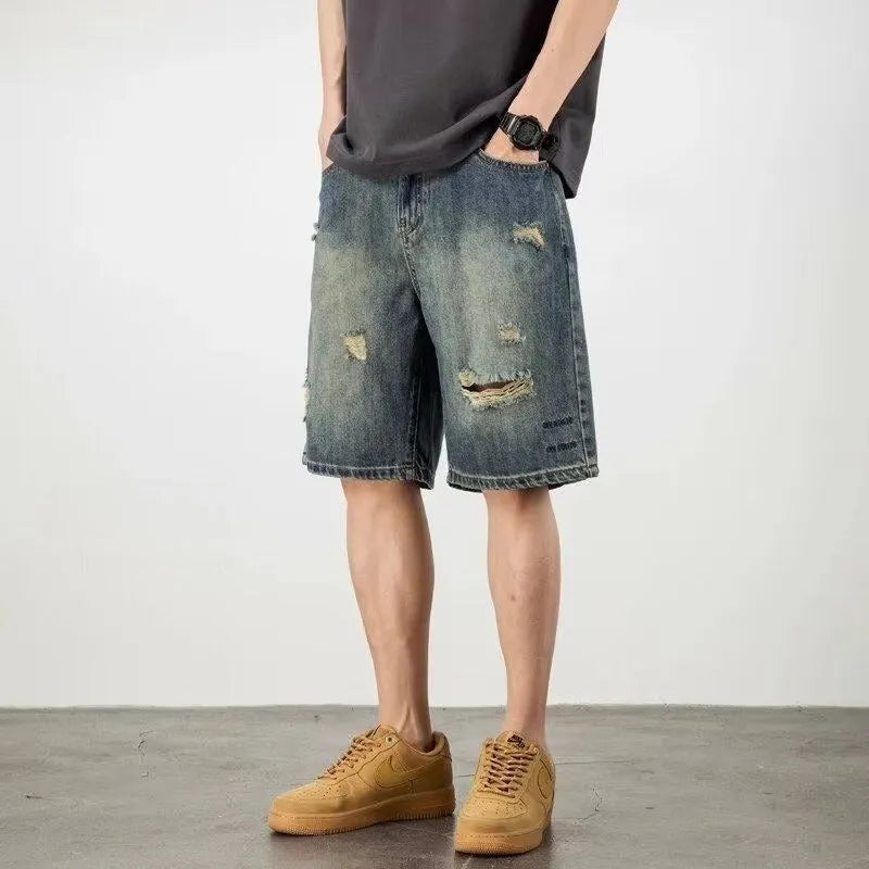 Man wearing blue retro loose hole distressed denim shorts with a straight leg cut
