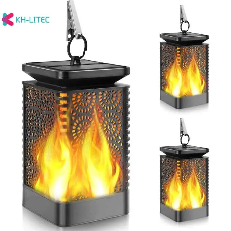 Four black solar-powered outdoor torch lights with flickering LED flame effect, placed on a garden patio.