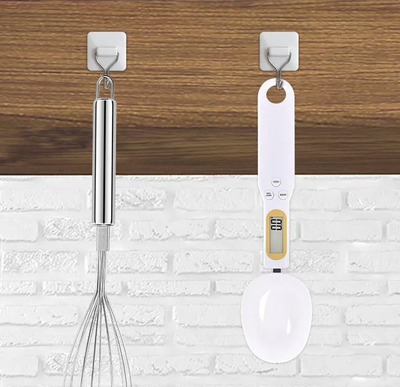 Black electronic measuring spoon scale on a kitchen counter showing digital display.