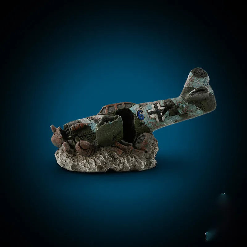 Resin simulated aircraft wreckage aquarium ornament 8cm by 4.5cm by 4.5cm on dark substrate