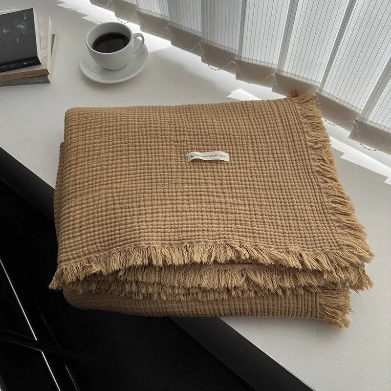 Cotton four-layer gauze blanket with tassel trim in avocado green colour, laid flat.