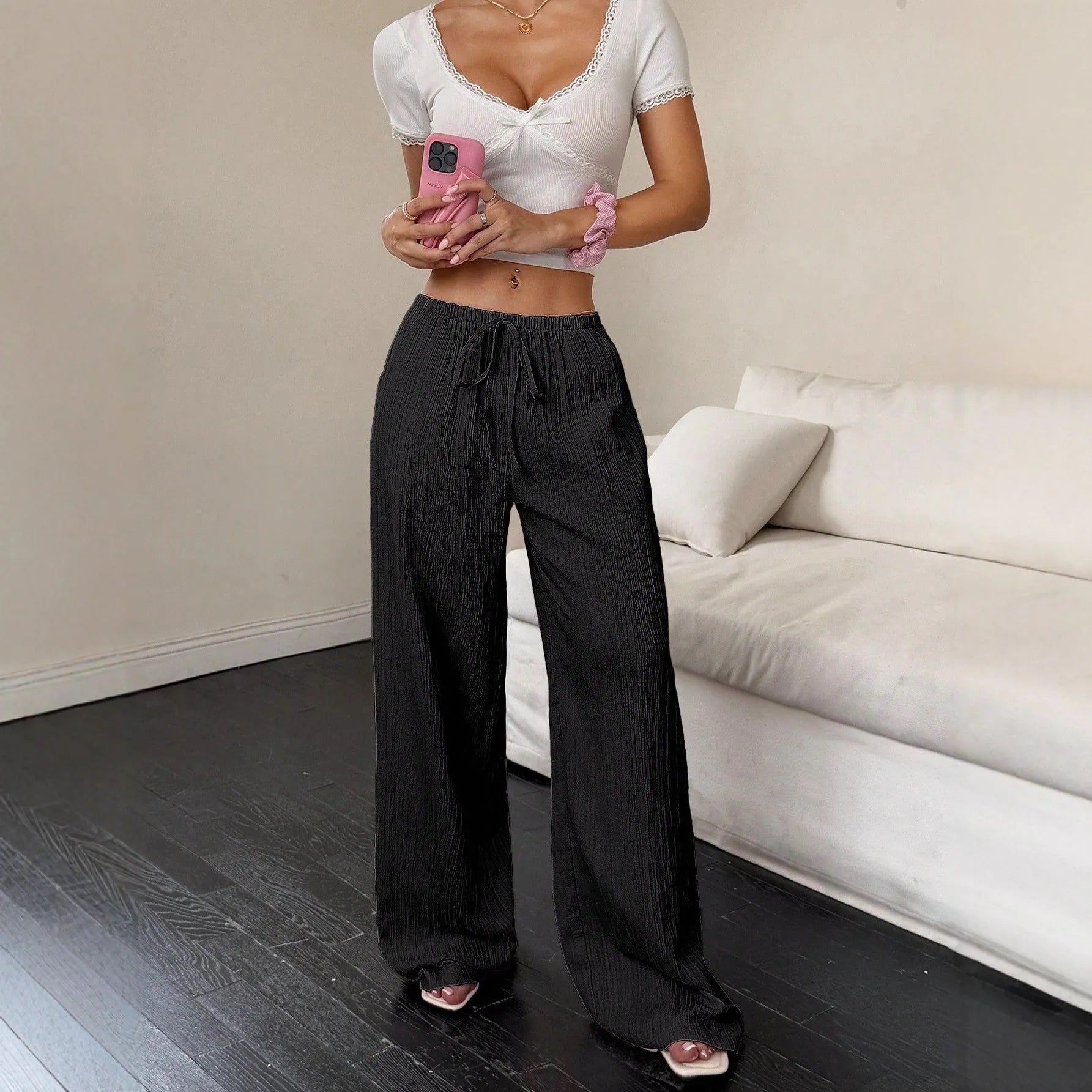 Women's black wide-leg trousers with a front lace-up waist detail, shown in a casual standing pose.