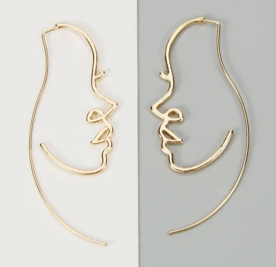 Creative abstract face contour earrings in metal gold finish on a white background