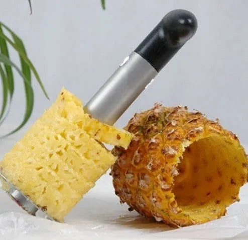 Stainless steel pineapple corer slicer with black plastic handle on a kitchen worktop.