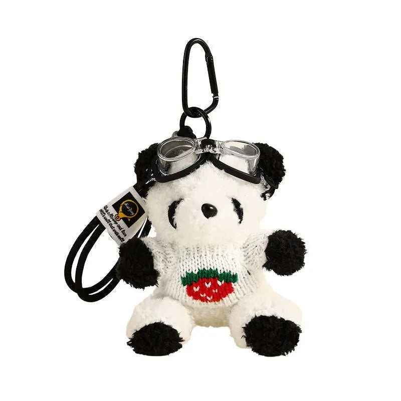 Cute plush strawberry bear doll keychain pendant on a soft surface, showing the cartoon bear with strawberry sweater design