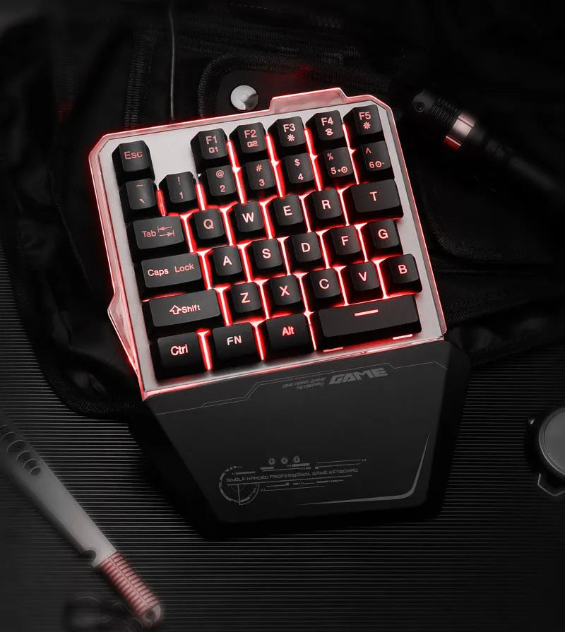 Black robotic one-handed keyboard with RGB backlit keys on a desk.