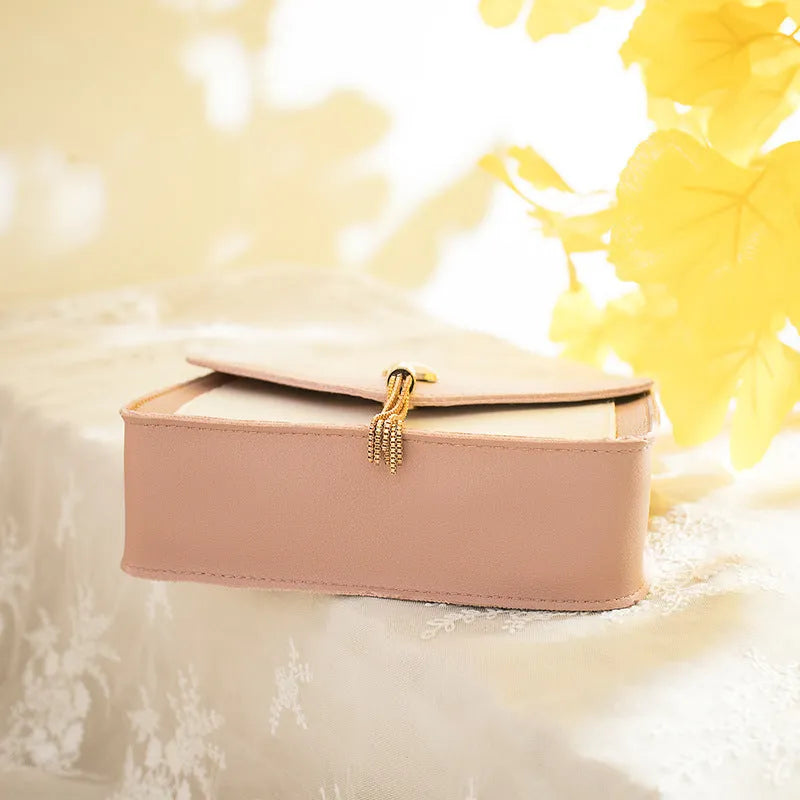 Small square PU leather messenger bag with cat tassel decoration and chain strap on a white background
