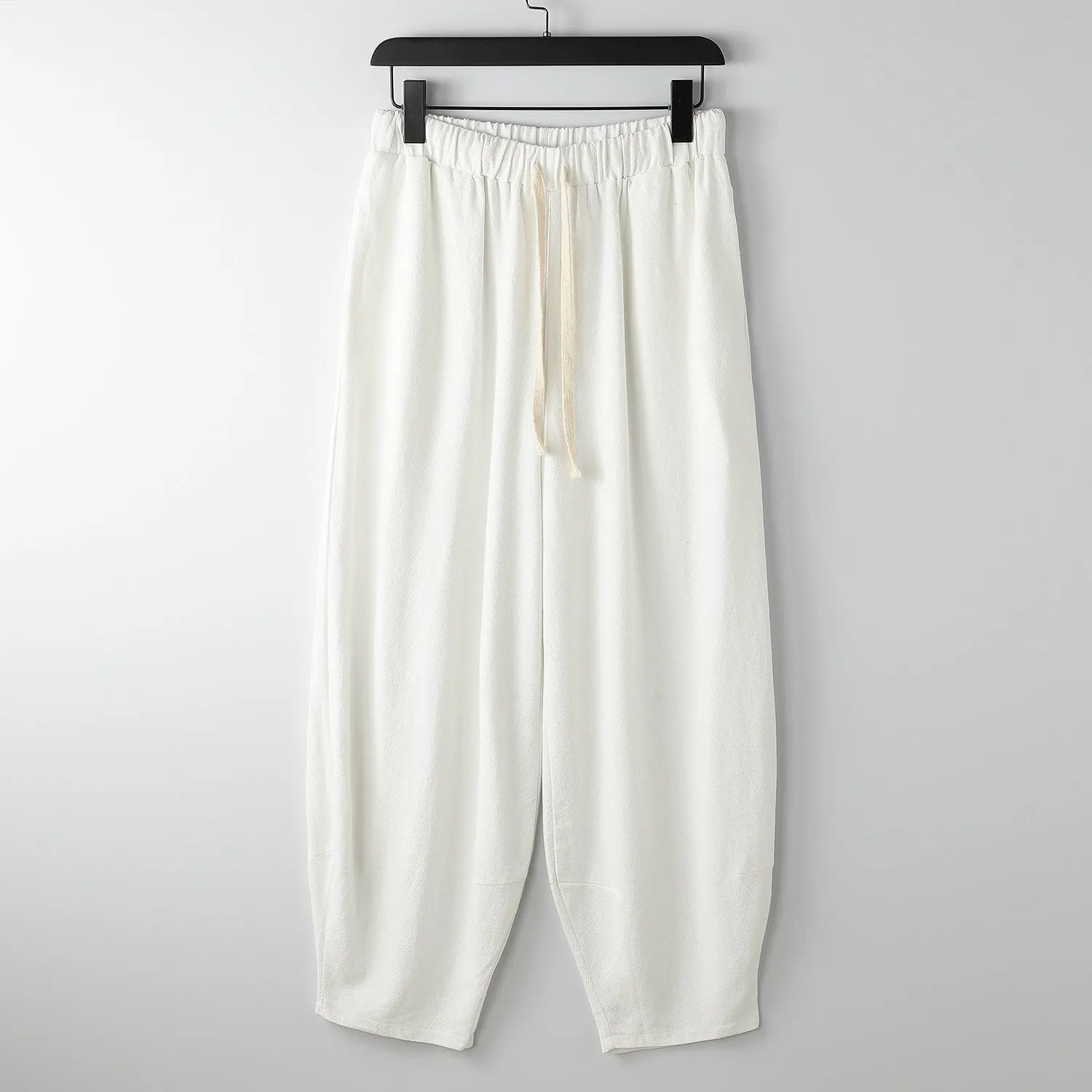 Linen harem pants for men with loose tapered fit and ankle-tied cuffs, shown in grey.