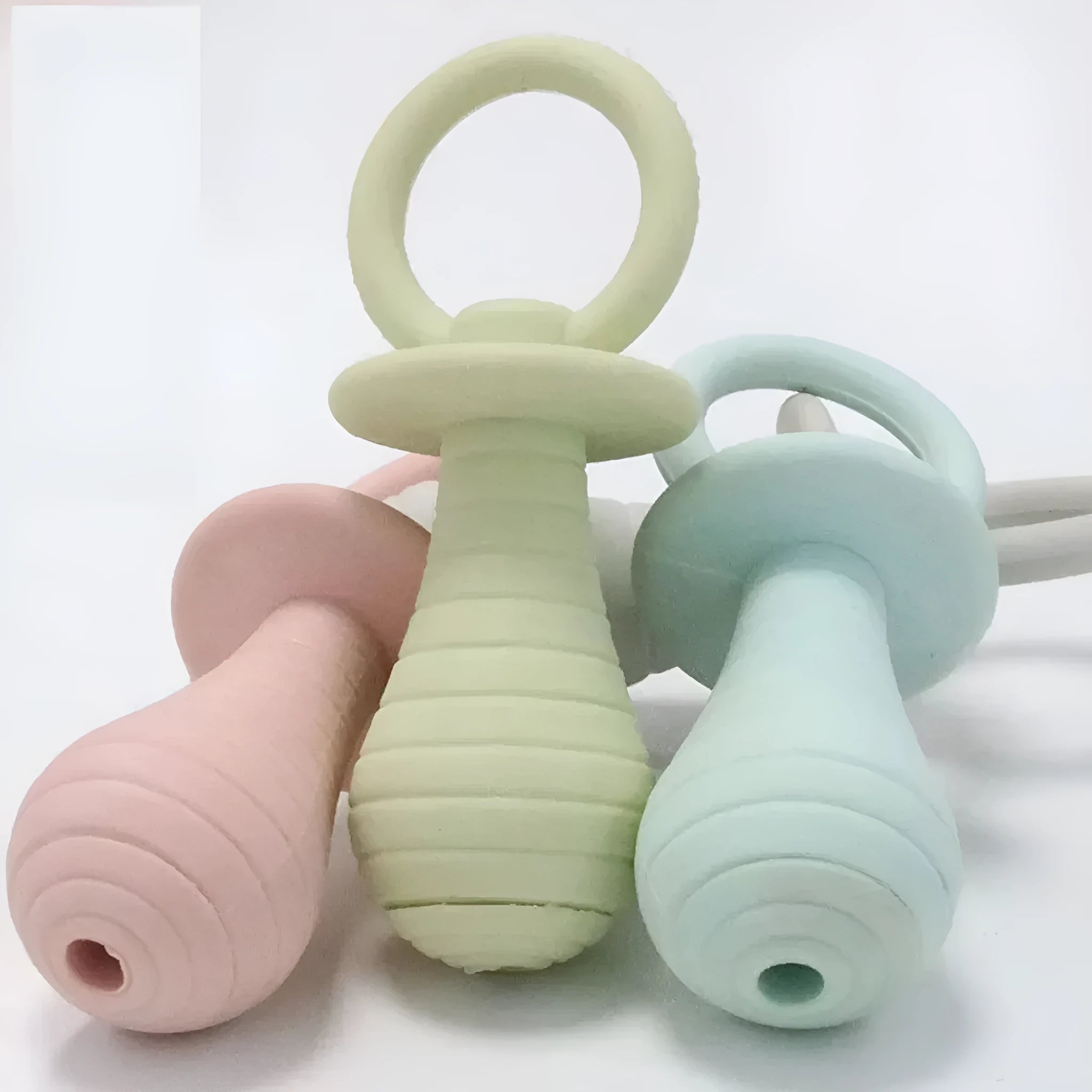 Four TPR rubber pet pacifier chew toys with squeakers in blue, grey, green, and pink colours