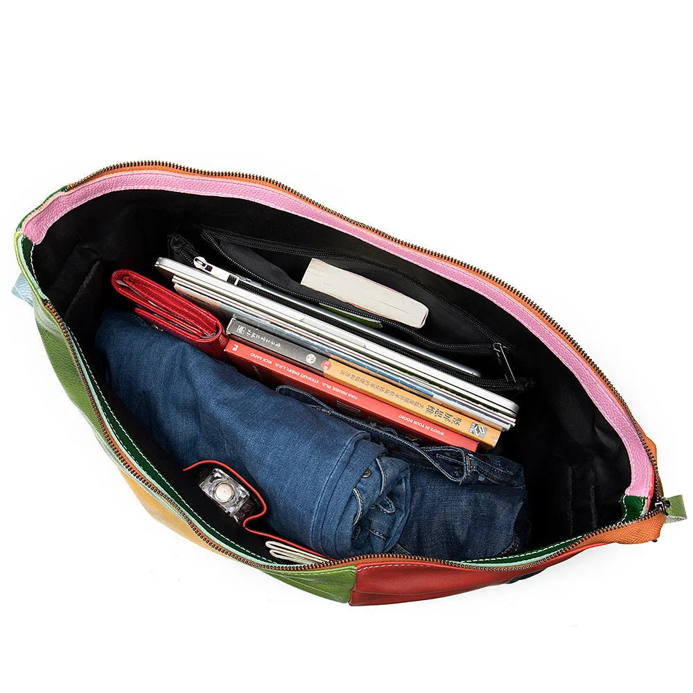 Brown cowhide leather crossbody travel bag showing main compartment open next to a 15-inch laptop and A4 magazine.