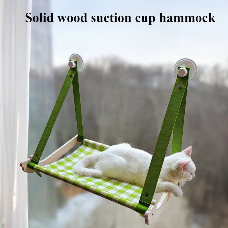 Green wooden cat window hammock with suction cups attached to glass, showing a removable linen mat.