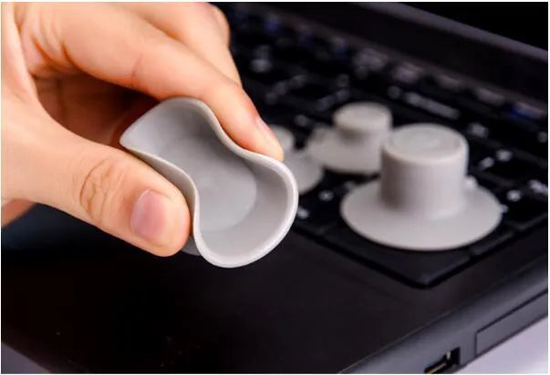 Set of four grey plastic laptop cooling pads with non-slip rubber feet, shown elevating a silver laptop.
