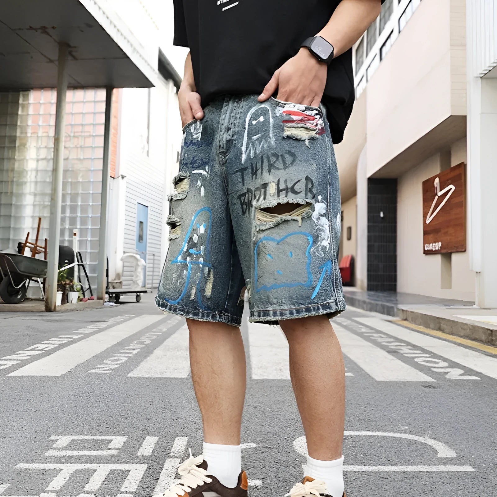 Blue men's ripped denim shorts with graffiti design and straight leg.
