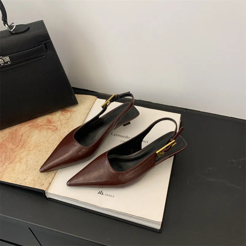Women's black pointed toe low heel shoes with an ankle strap and rubber sole.