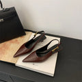 Women's black pointed toe low heel shoes with an ankle strap and rubber sole.