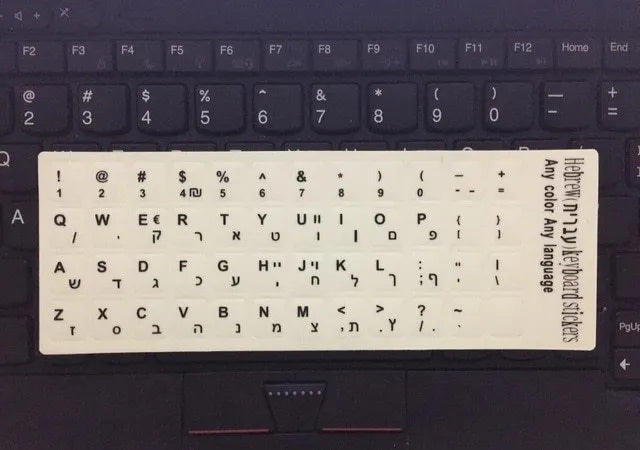 Glowing yellow multilingual keyboard stickers showing Arabic, Thai, Hebrew, French, Italian and German characters