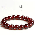 Close-up of a natural orange red garnet bead bracelet with a metal Ruyi charm on a wrist.