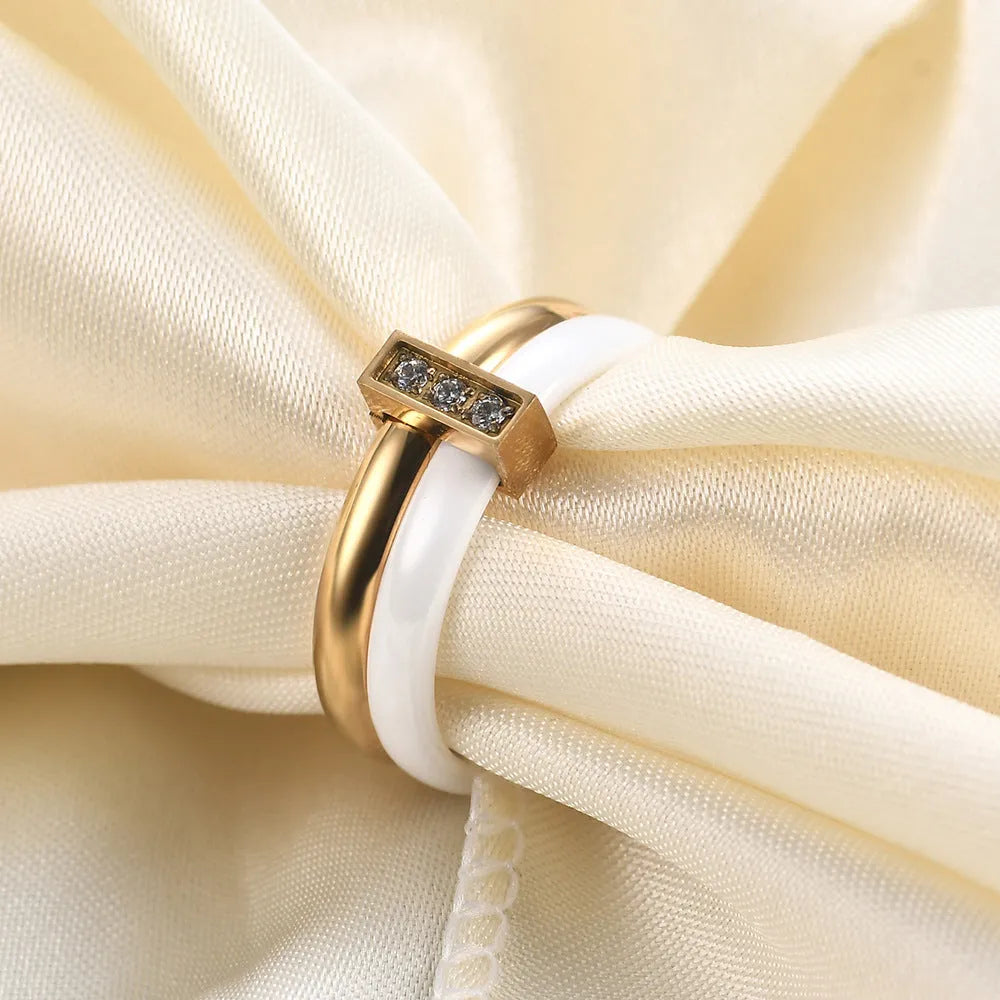 A Steel Black ceramic women's ring with glossy stitching and inlaid zirconium stones on a wooden surface.