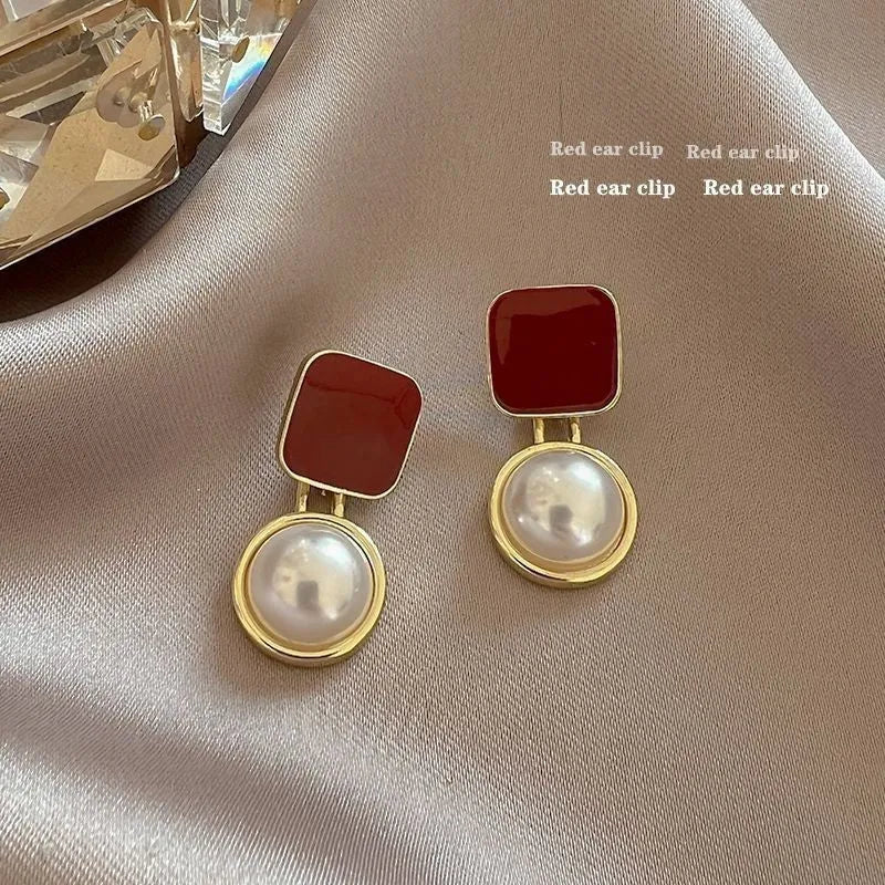 Red and blue geometric alloy stud earrings with pearl centre on neutral background