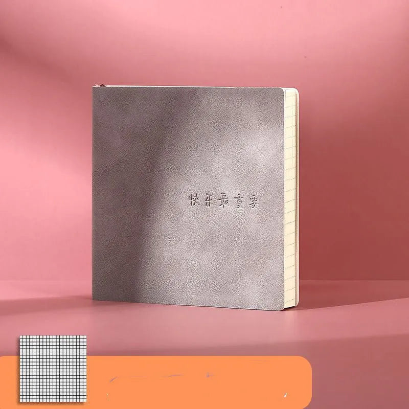 Square faux leather notebook open on a table, showing Daolin paper and French fold binding.