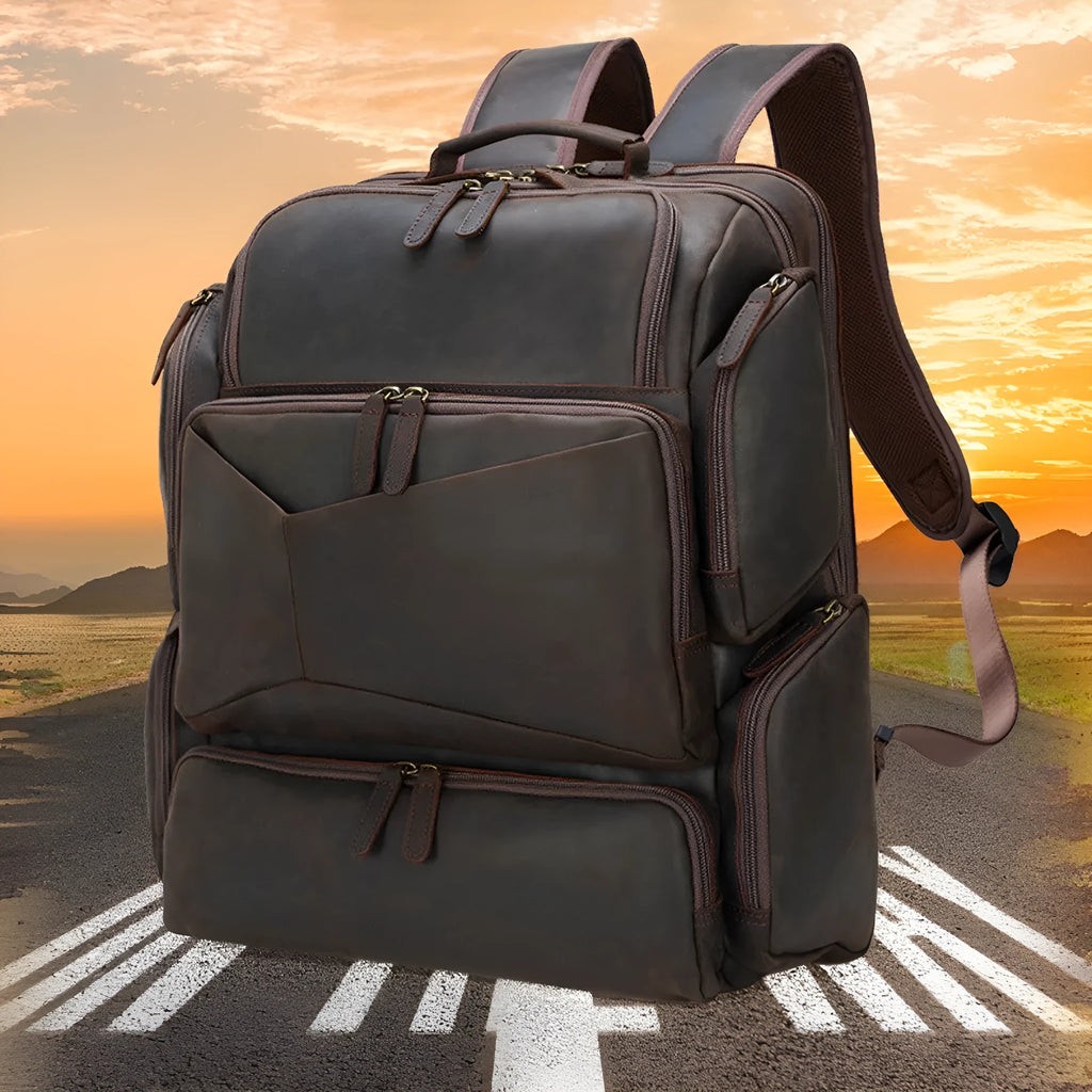 Dark brown genuine leather men's backpack open to show 17-inch laptop compartment and internal organiser pockets.