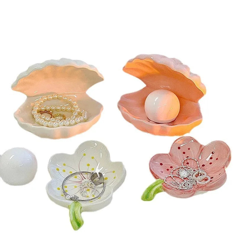 White and pink porcelain shell-shaped tray with integrated yellow LED night light on a wooden table.