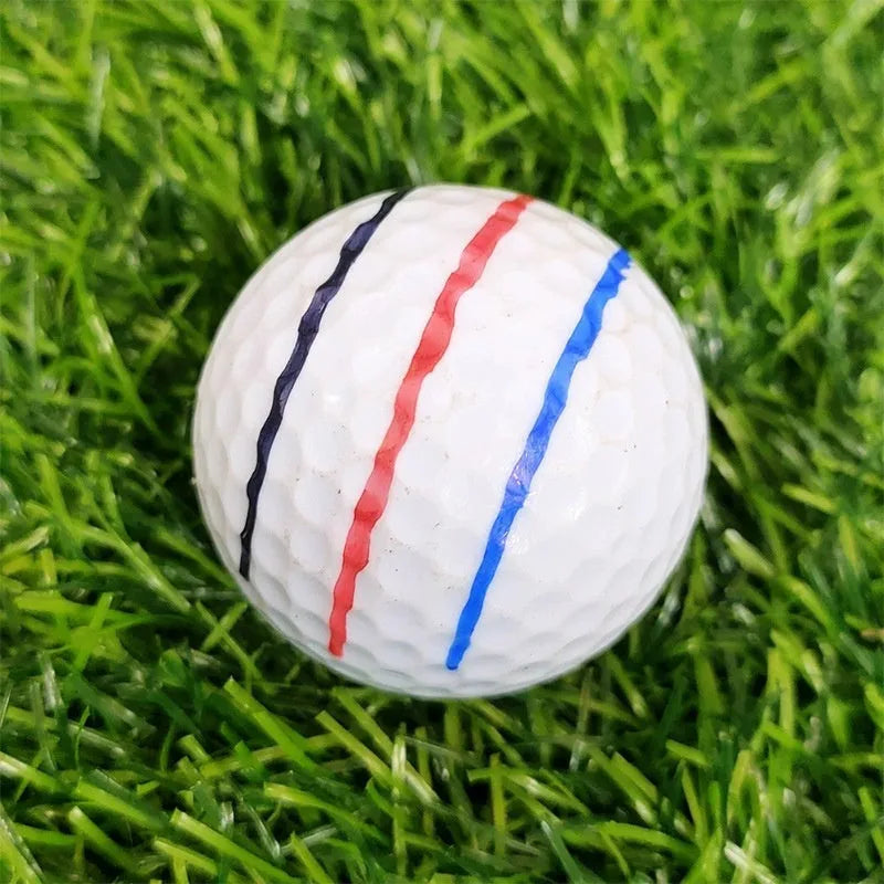 White plastic golf putting alignment tool holding four metal scribers, with a drawing pen inserted in the side holder, on a green golf putting mat.