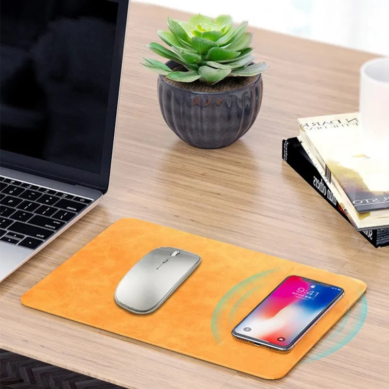 Brown leather-texture wireless charging mouse pad with a phone placed on it charging, on a wooden desk.