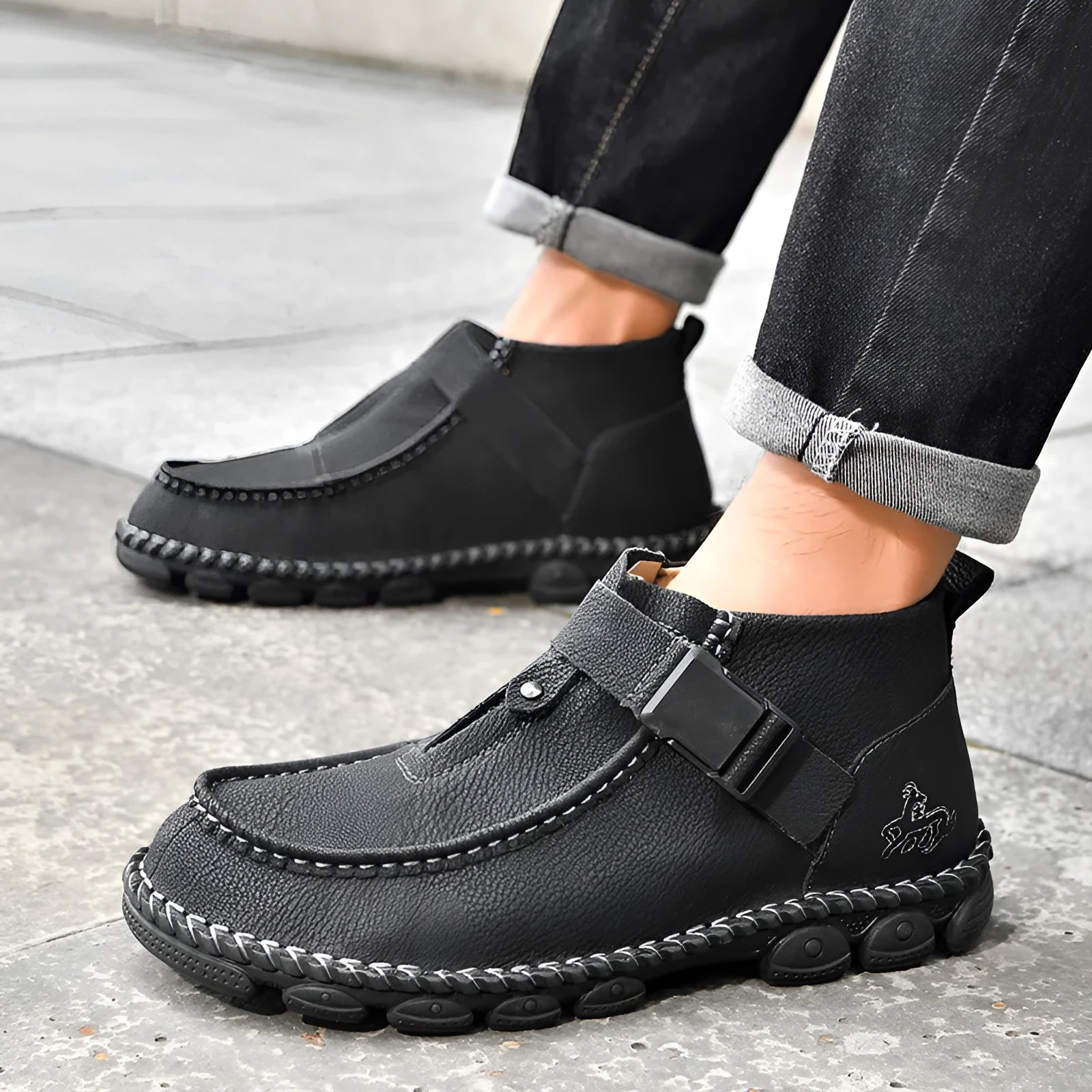 Men's black synthetic leather slip-on shoes with visible handmade stitching and a flat sole
