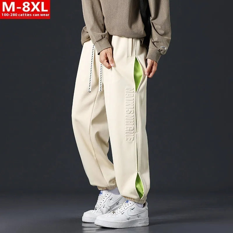 Man wearing loose-fit black trousers with printed stitching detail and a banded ankle cuff.
