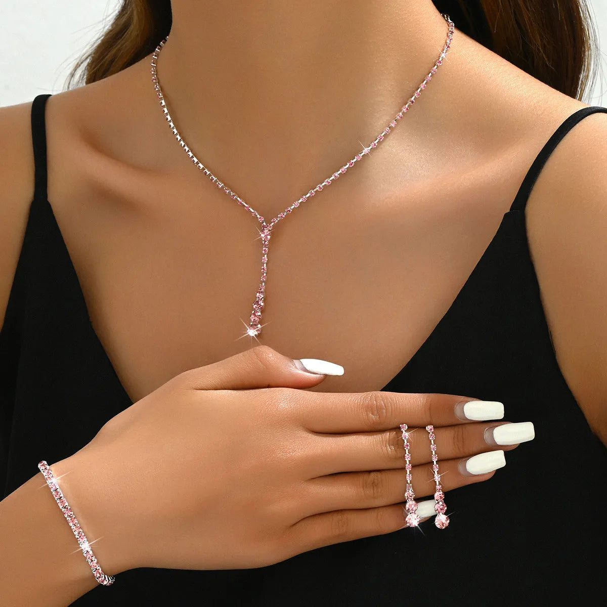 Women's three-piece bridal jewellery set showing earrings, necklace and bracelet with rhinestone heart-shaped pendant