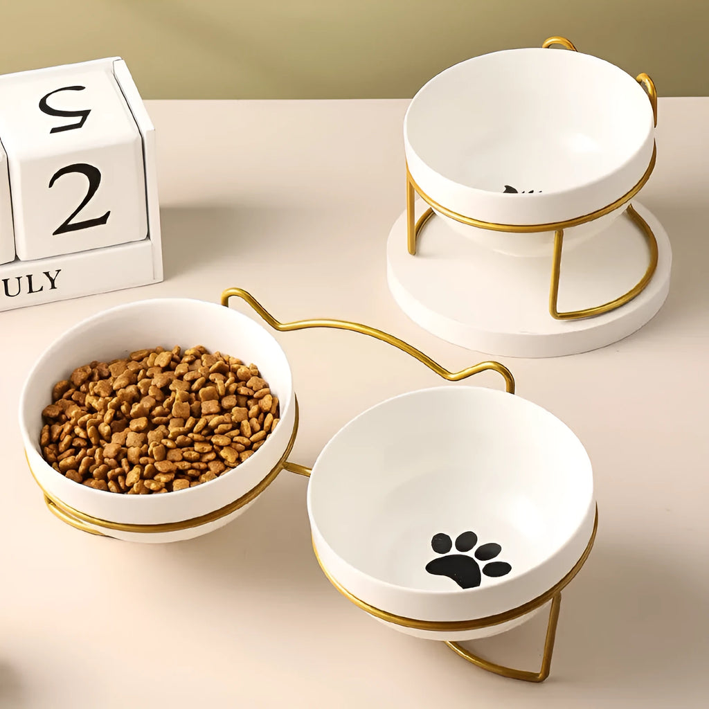 White ceramic cat bowl with cat footprint design on a black iron stand with cat ears.